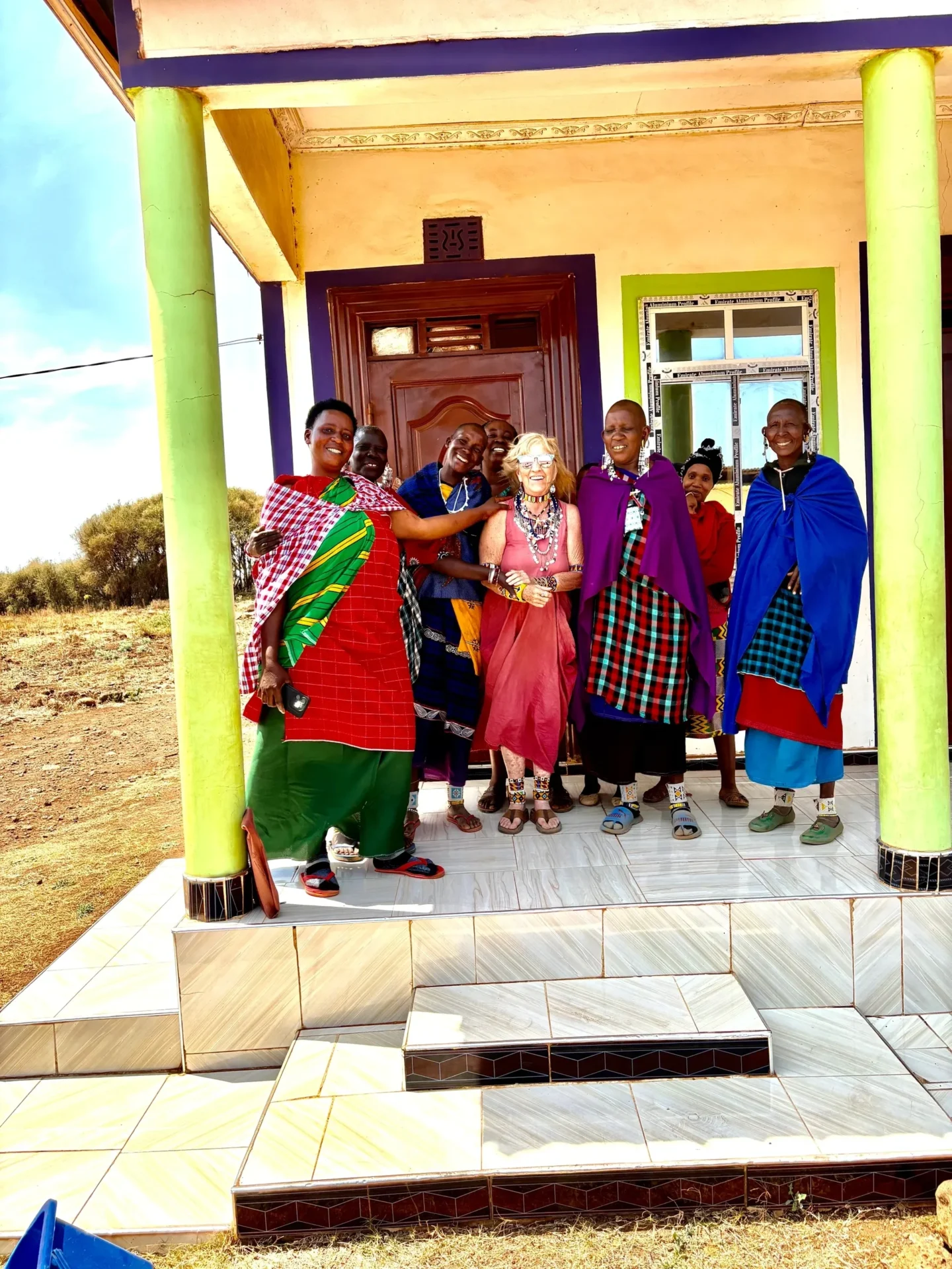 Group of people smiling outside colorful building.