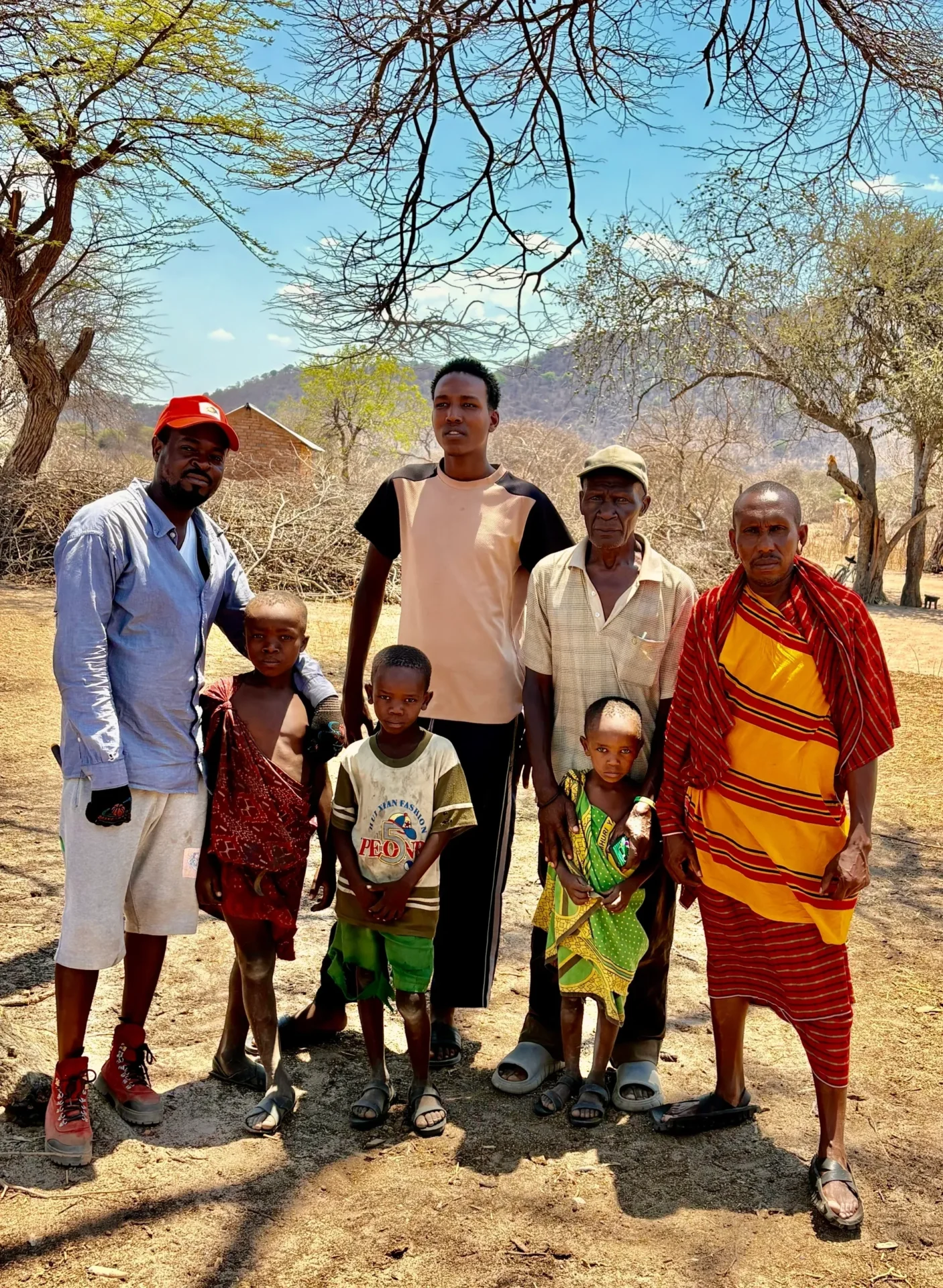Group of people standing outdoors, trees behind.