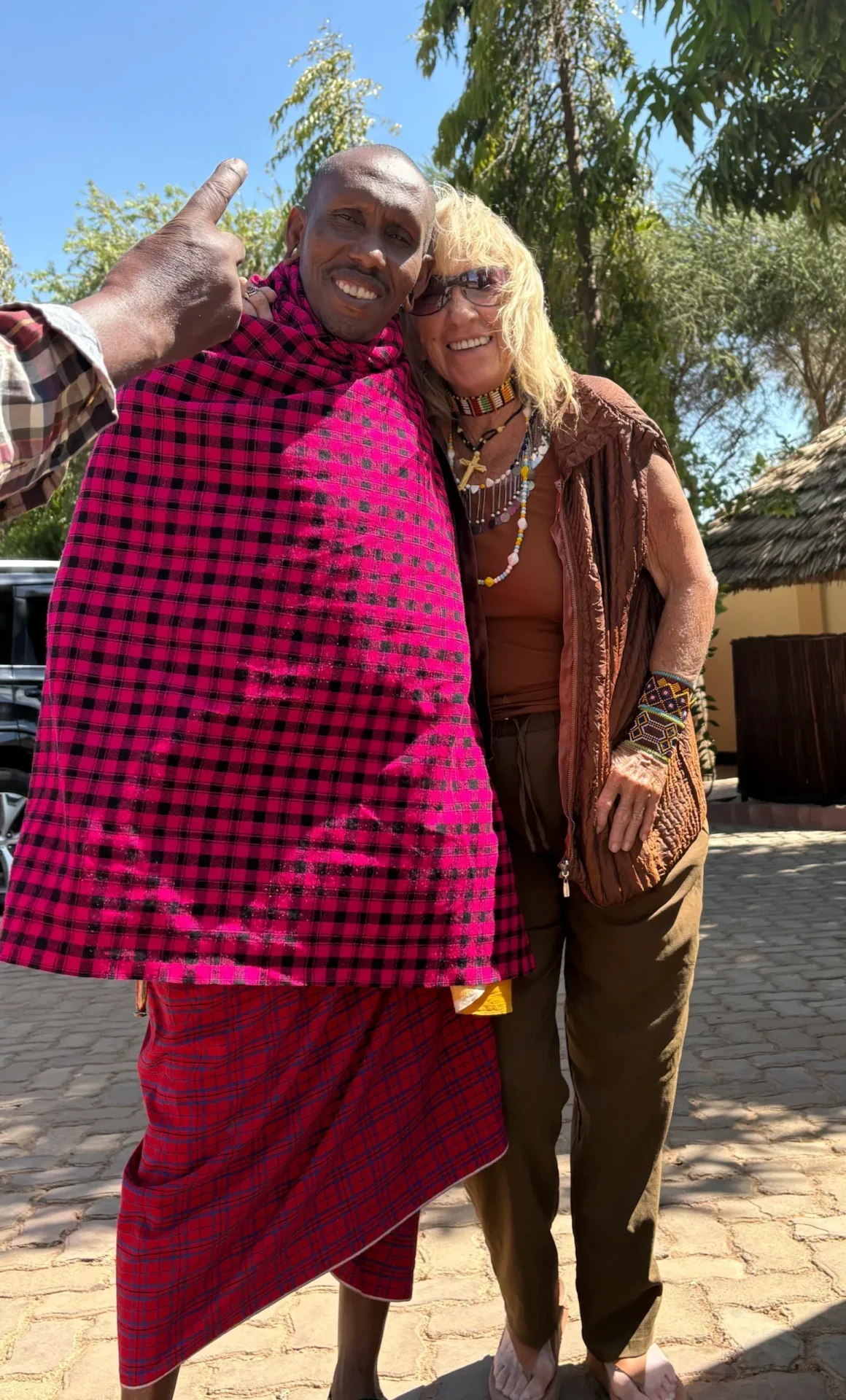 Two people smiling outdoors, one wearing plaid.