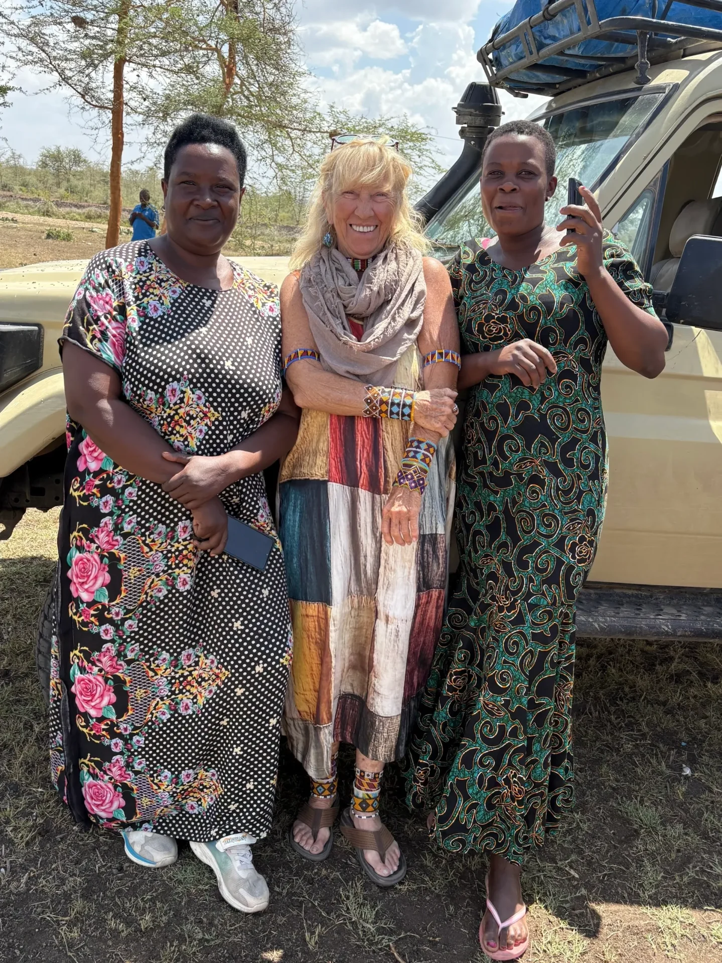 Three women standing in front of vehicle.