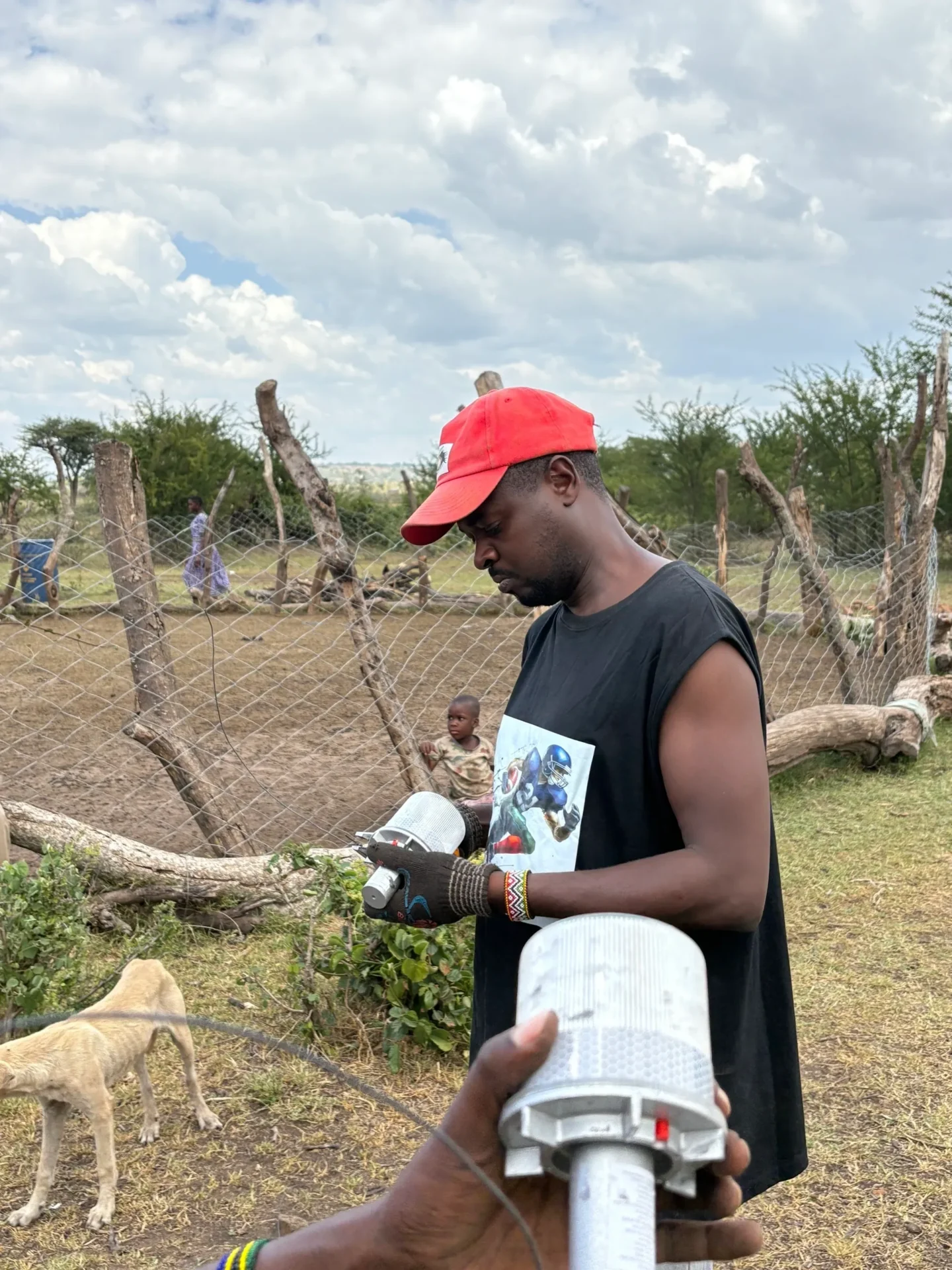 Man with red cap holding a device.