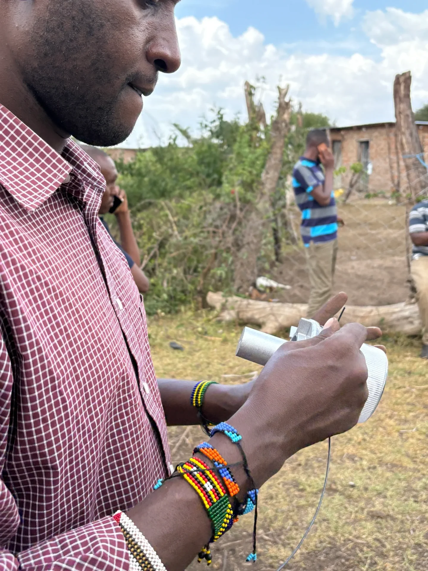 Man holding a camera, wearing colorful bracelets.